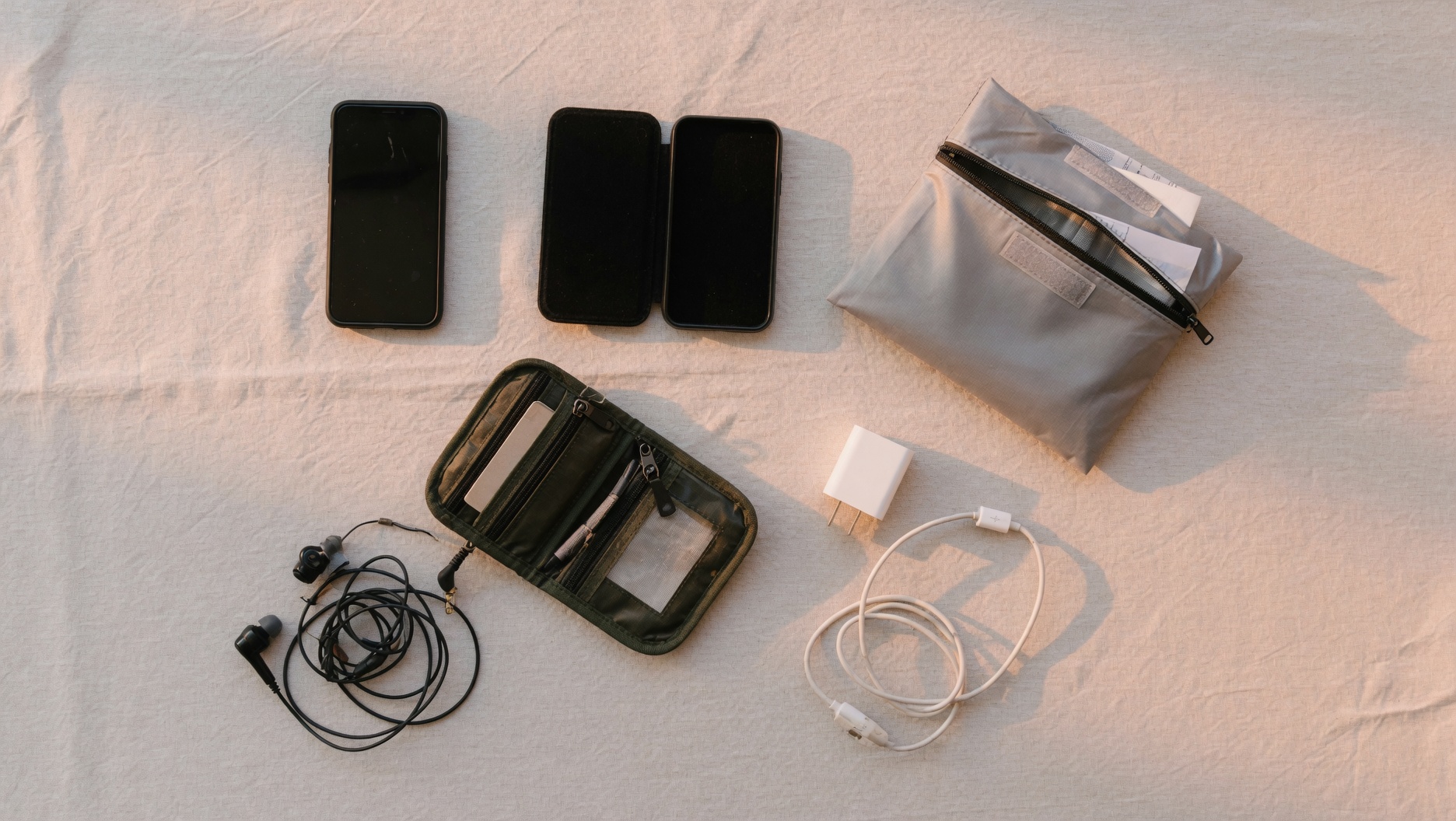 Starter kit arrangement with dumbphone, pouch, earbuds, and charging accessories