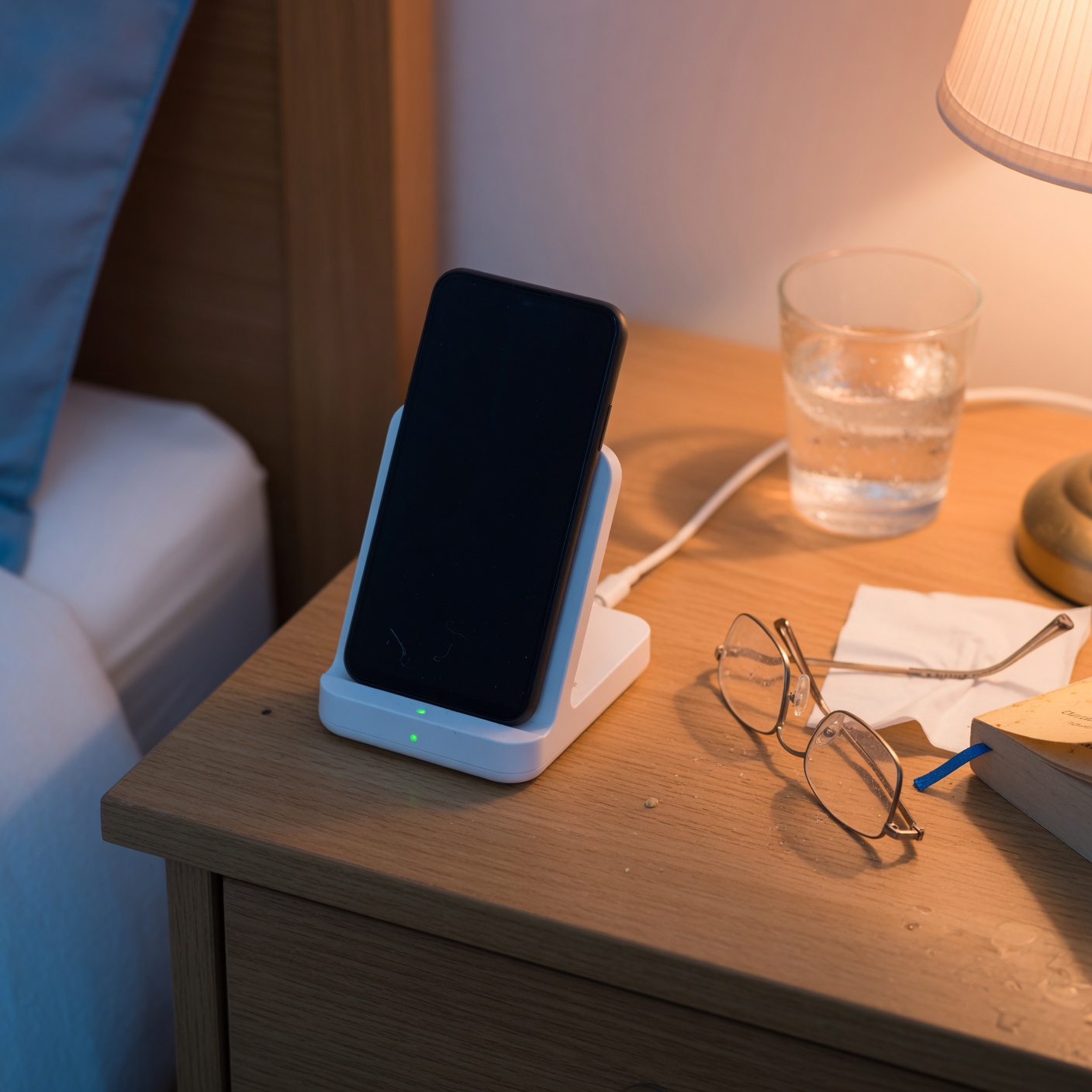 Simple phone resting in charging cradle on a bedside table